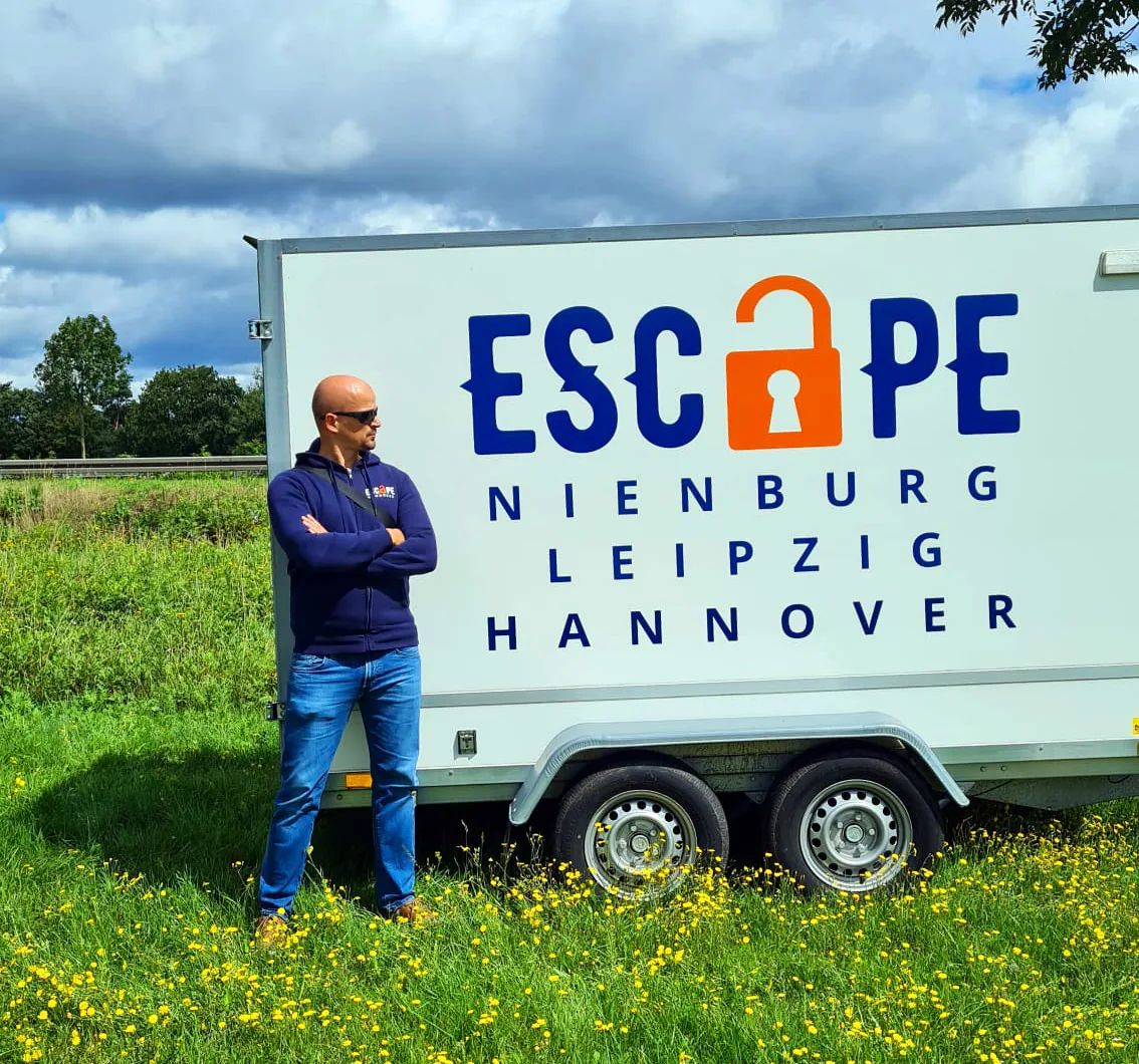 Artur Hammerschmidt mit verschränkten Armen vor dem Escape-Anhänger mit den Standorten Nienburg, Leipzig und Hannover